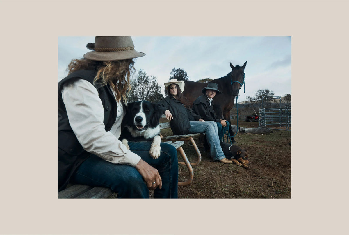 People sitting with a dog and horse in an outdoor setting, wearing Driza-Bone Heavyweight Vests and Jackets