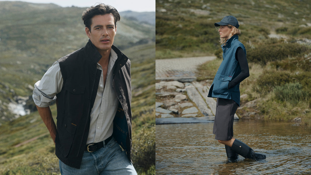 A split-screen outdoor lifestyle image showing a man on the left wearing a black sleeveless vest over a light shirt and jeans, and a woman on the right wearing a matching dark teal vest, dark shorts, black rain boots, and a cap while standing in shallow water.